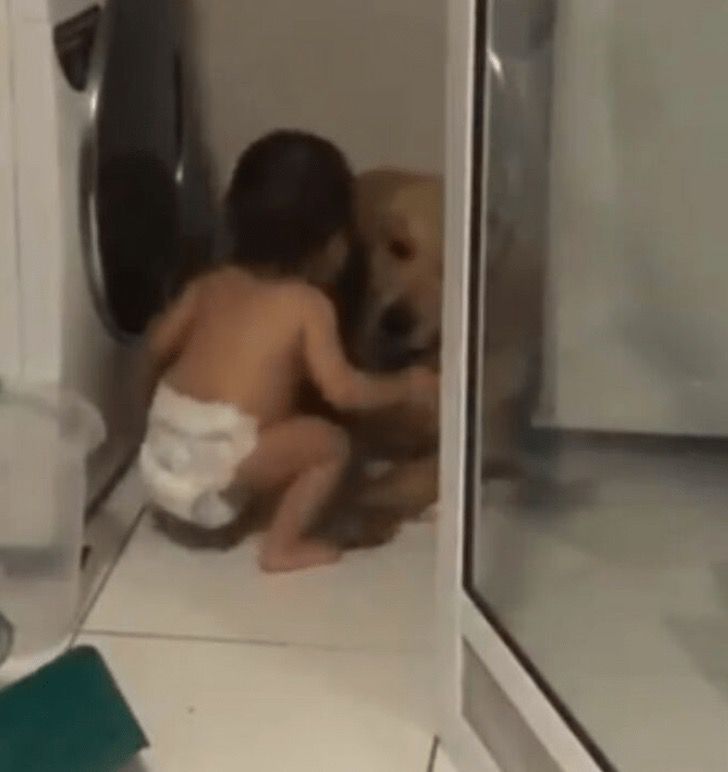 Bebé abraza a su perro para tratar de calmarlo durante una tormenta.
